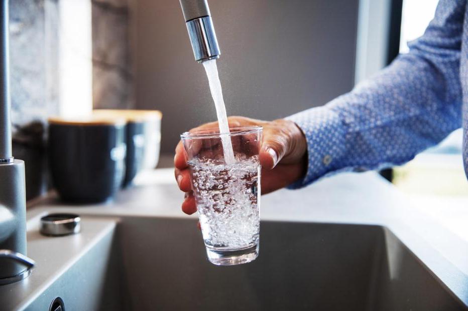 man filling glass of water from faucet